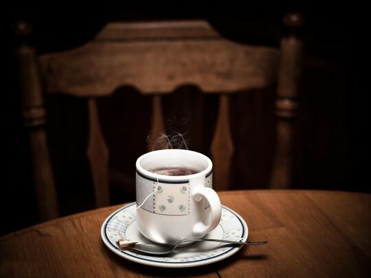 Tasse à soucoupe de café posée sur une table ronde avec une chaise rustique en arrière-plan